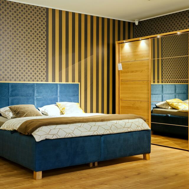 Petrolblauwe boxspring van velours met houten omlijsting en poten