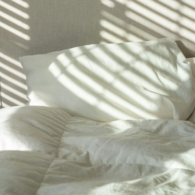 Wit opgemaakt bed met kussen in warm ochtendlicht
